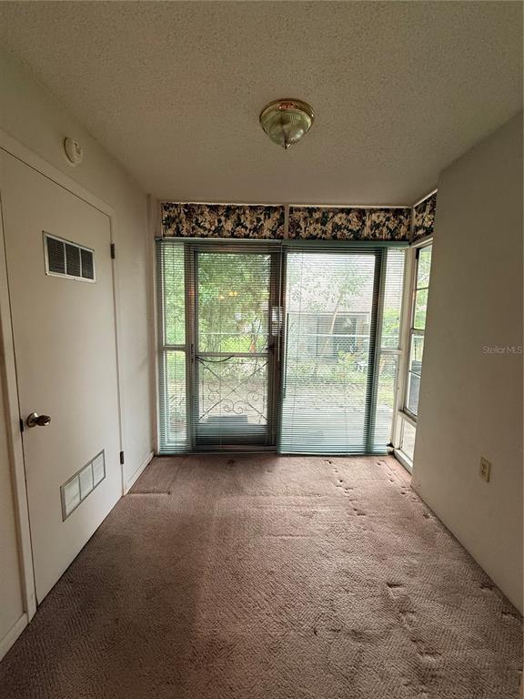 A sunroom with brown carpet, a glass sliding door, and a floral valance — 155 N HILL AVENUE UNIT 80, DELAND, FL