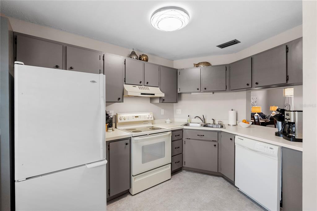 A kitchen with gray cabinets, white appliances, and light-colored countertops — 8703 BARDMOOR BOULEVARD UNIT 305, SEMINOLE, FL