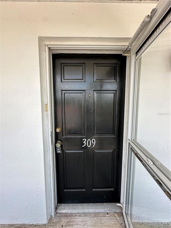 A black front door with the number 309 is set within a white exterior wall — 100 EL CAMINO DRIVE UNIT 309, WINTER HAVEN, FL
