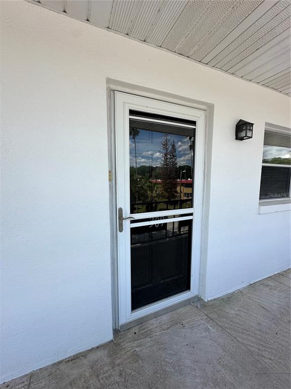 A white exterior door with a glass storm door sits on a concrete walkway — 100 EL CAMINO DRIVE UNIT 309, WINTER HAVEN, FL