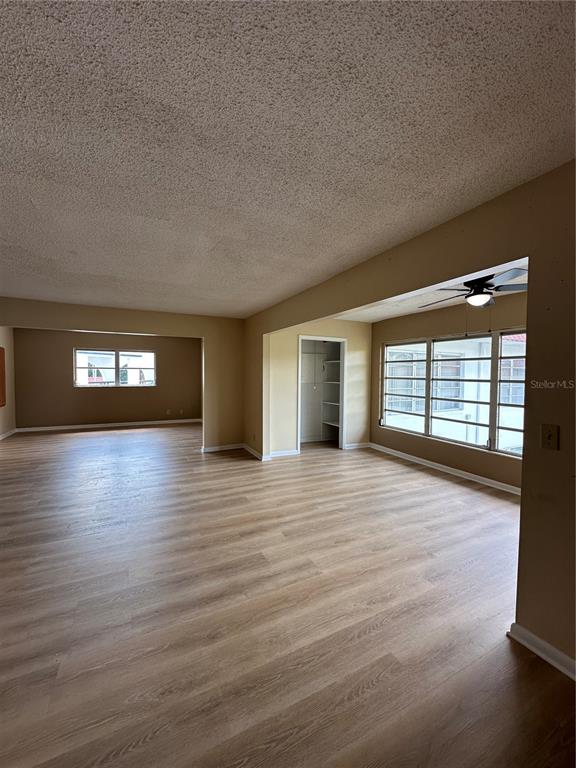 An open-concept living area features light wood-look flooring, a popcorn ceiling, and large windows — 100 EL CAMINO DRIVE UNIT 309, WINTER HAVEN, FL
