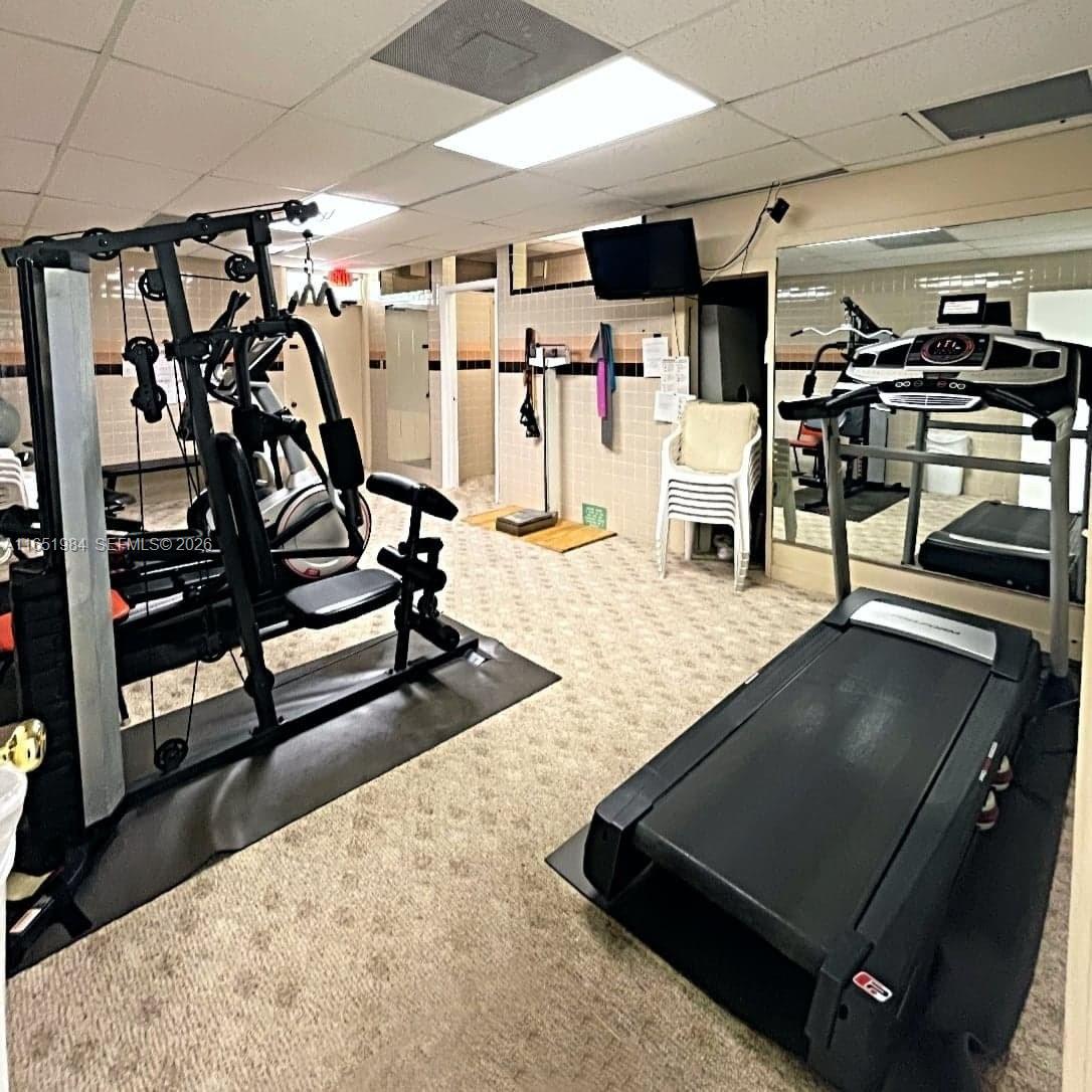 This gym features a multi-station weight machine, a treadmill, and tiled walls — 6100 NW 44th St # 405, Lauderhill FL 33319, LAUDERHILL, FL