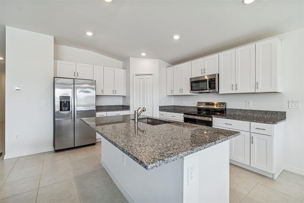 A single-story house with a white exterior, a dark garage door, and a front lawn — 4530 COZY CONDOR COURT, BARTOW, FL