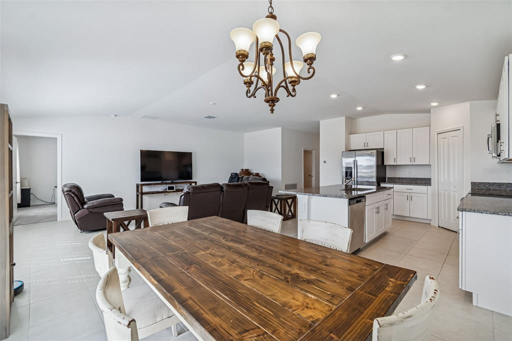 An open-concept kitchen and dining area features a wooden table, chandelier, and white cabinetry — 4530 COZY CONDOR COURT, BARTOW, FL