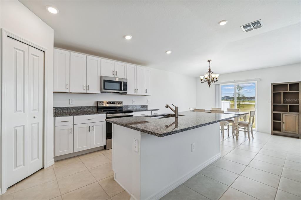 A kitchen with white cabinets, granite countertops, stainless steel appliances, and a central island — 4530 COZY CONDOR COURT, BARTOW, FL