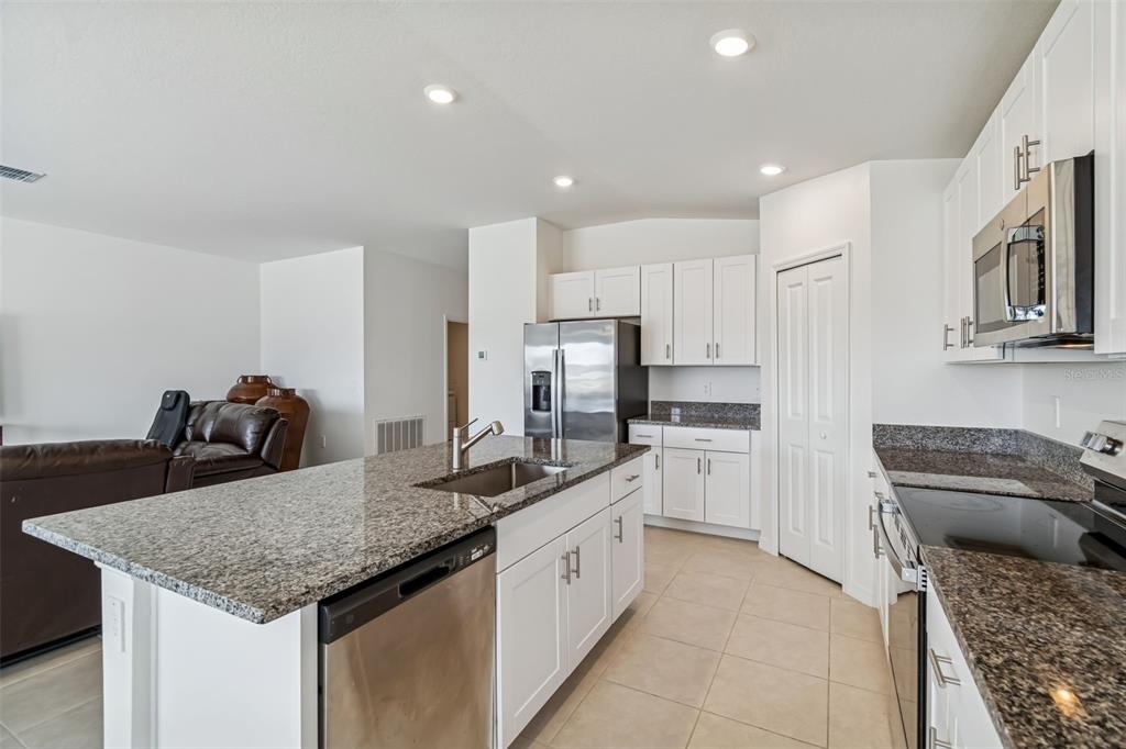 A kitchen with white cabinets, granite countertops, a center island, and an adjacent dining area — 4530 COZY CONDOR COURT, BARTOW, FL