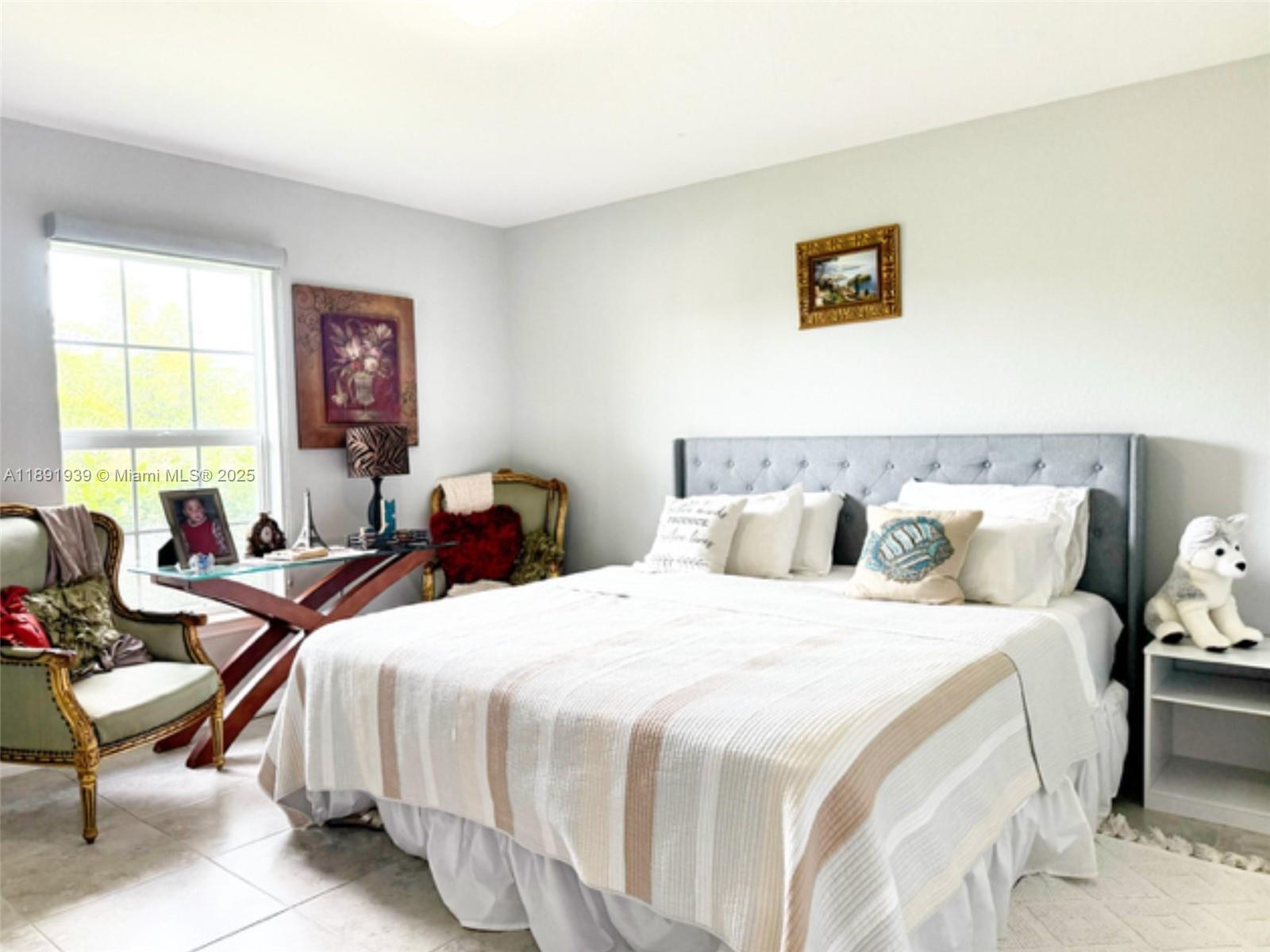 A bedroom features a tufted gray headboard, a striped bedspread, and a glass-topped desk — 4157 NW 40th ave, Cape Coral FL 33993, CAPE CORAL, FL