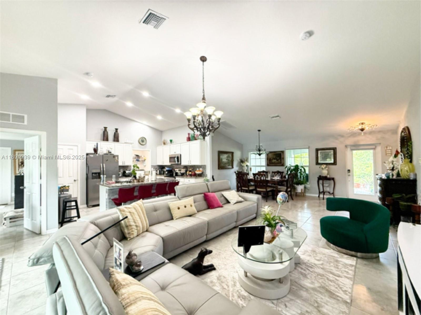An open-concept living and dining area features a large sectional sofa and kitchen island — 4157 NW 40th ave, Cape Coral FL 33993, CAPE CORAL, FL