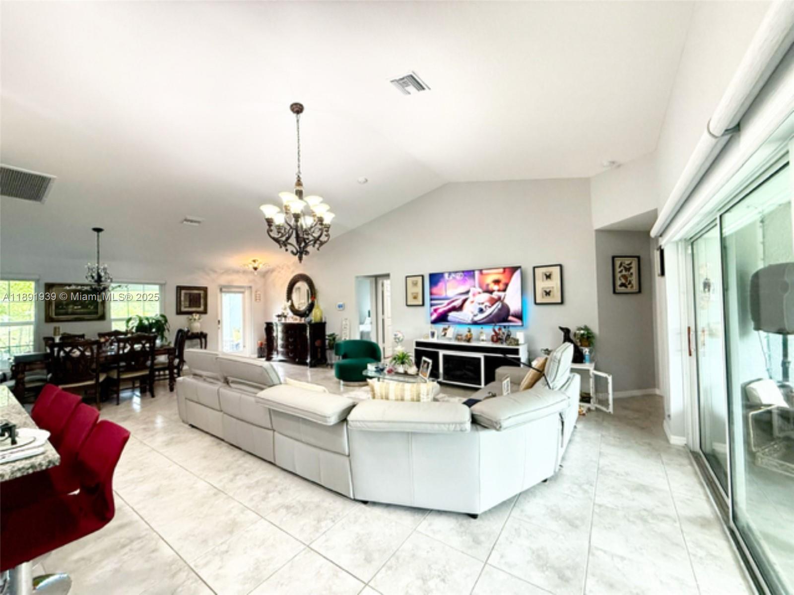 A spacious living room features a large sectional sofa, a television, and tile flooring — 4157 NW 40th ave, Cape Coral FL 33993, CAPE CORAL, FL