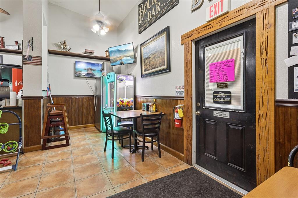 A small dining area features a table, chairs, a claw machine, and a wooden door — 36721 COUNTY ROAD 19A, EUSTIS, FL