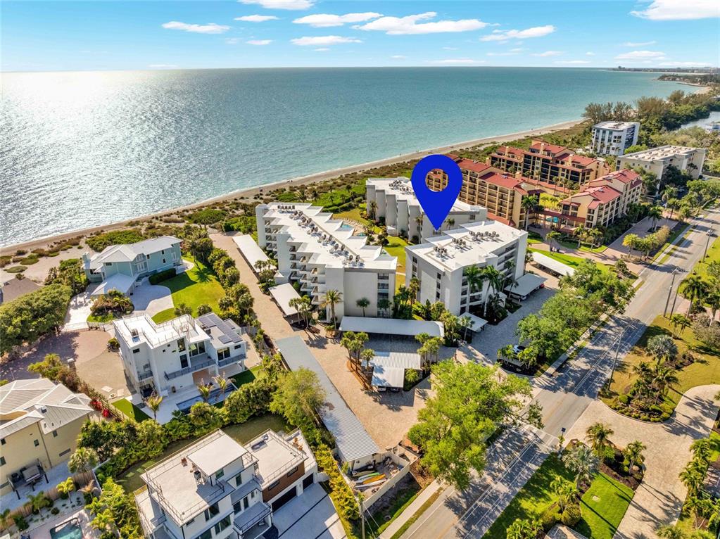 An aerial view shows a multi-story beachfront condominium complex with a blue location marker — 8764 MIDNIGHT PASS ROAD UNIT A201, SARASOTA, FL