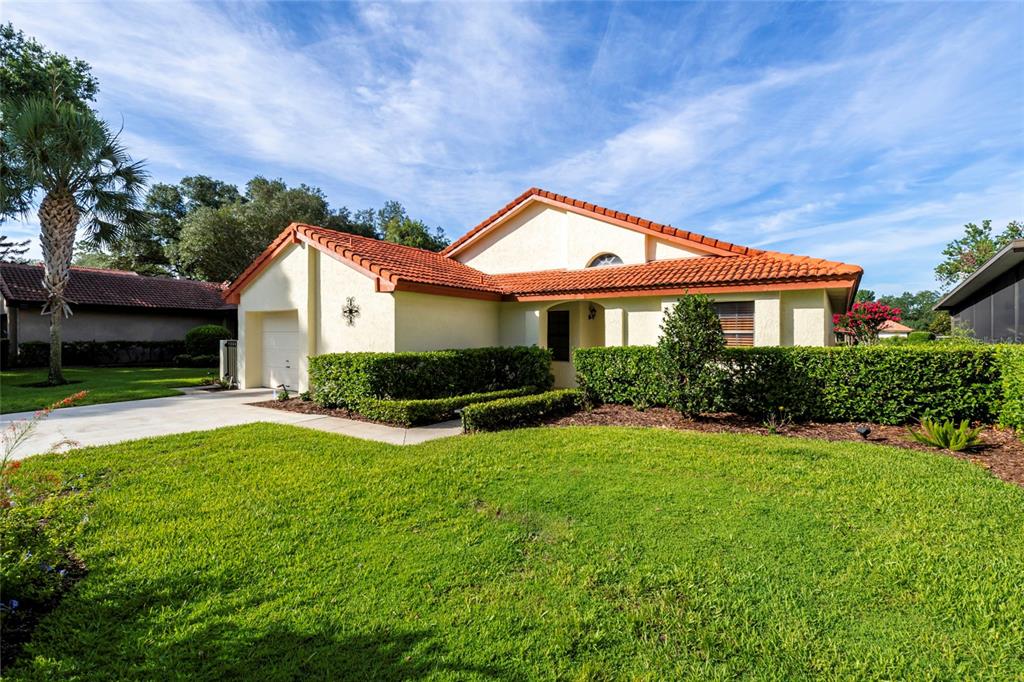 A single-story house with a red tile roof, beige stucco walls, and a manicured hedge — 6350 PARSON BROWN DRIVE, ORLANDO, FL