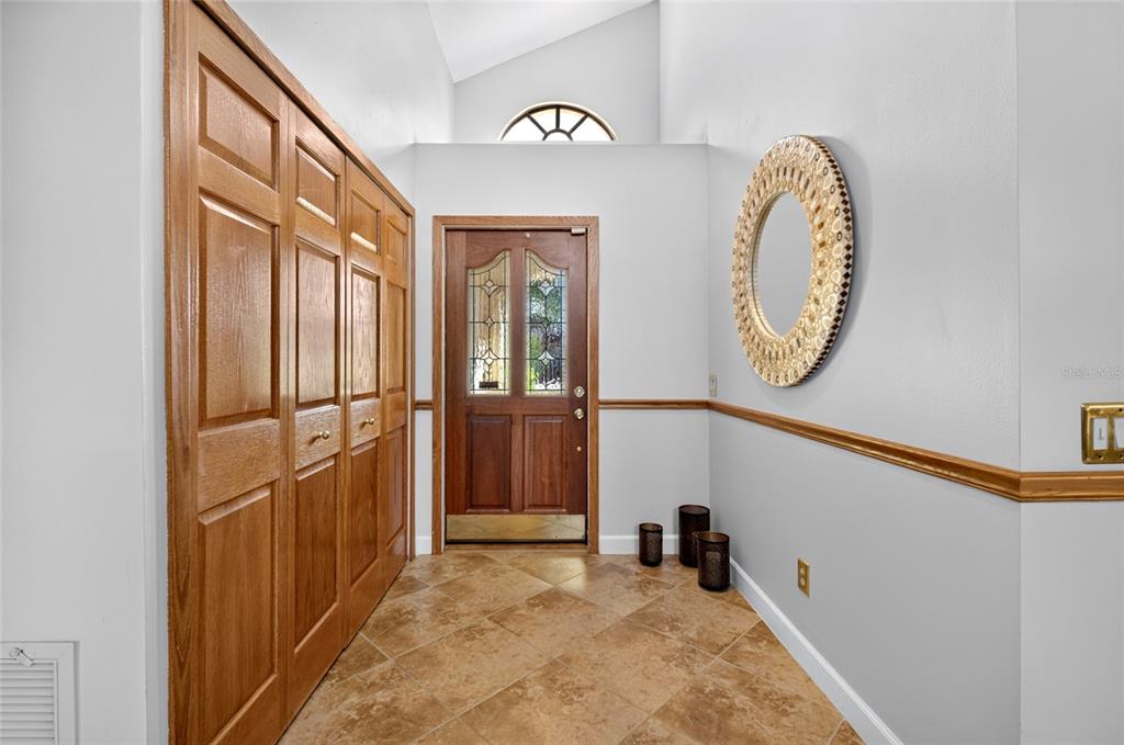 An entryway features a wood front door, tiled floor, large closet, and a decorative mirror — 6350 PARSON BROWN DRIVE, ORLANDO, FL