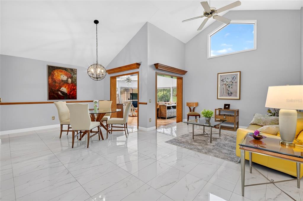 A bright open-concept living and dining area features vaulted ceilings, white tile floors, and wood trim — 6350 PARSON BROWN DRIVE, ORLANDO, FL