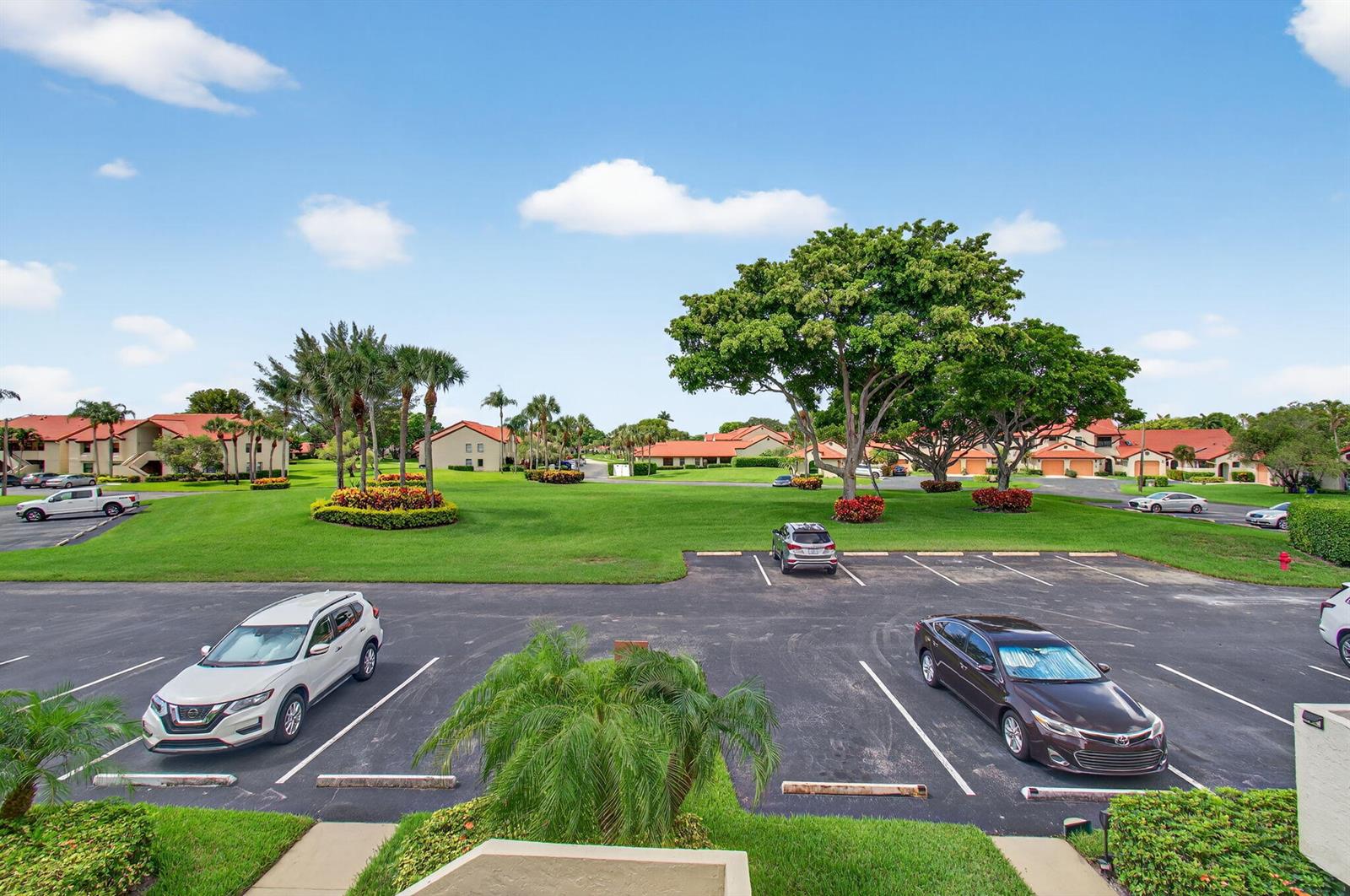 An elevated view of a parking lot surrounded by green lawns and residential buildings — 5947 Parkwalk Drive, Boynton Beach FL 33472, BOYNTON BEACH, FL