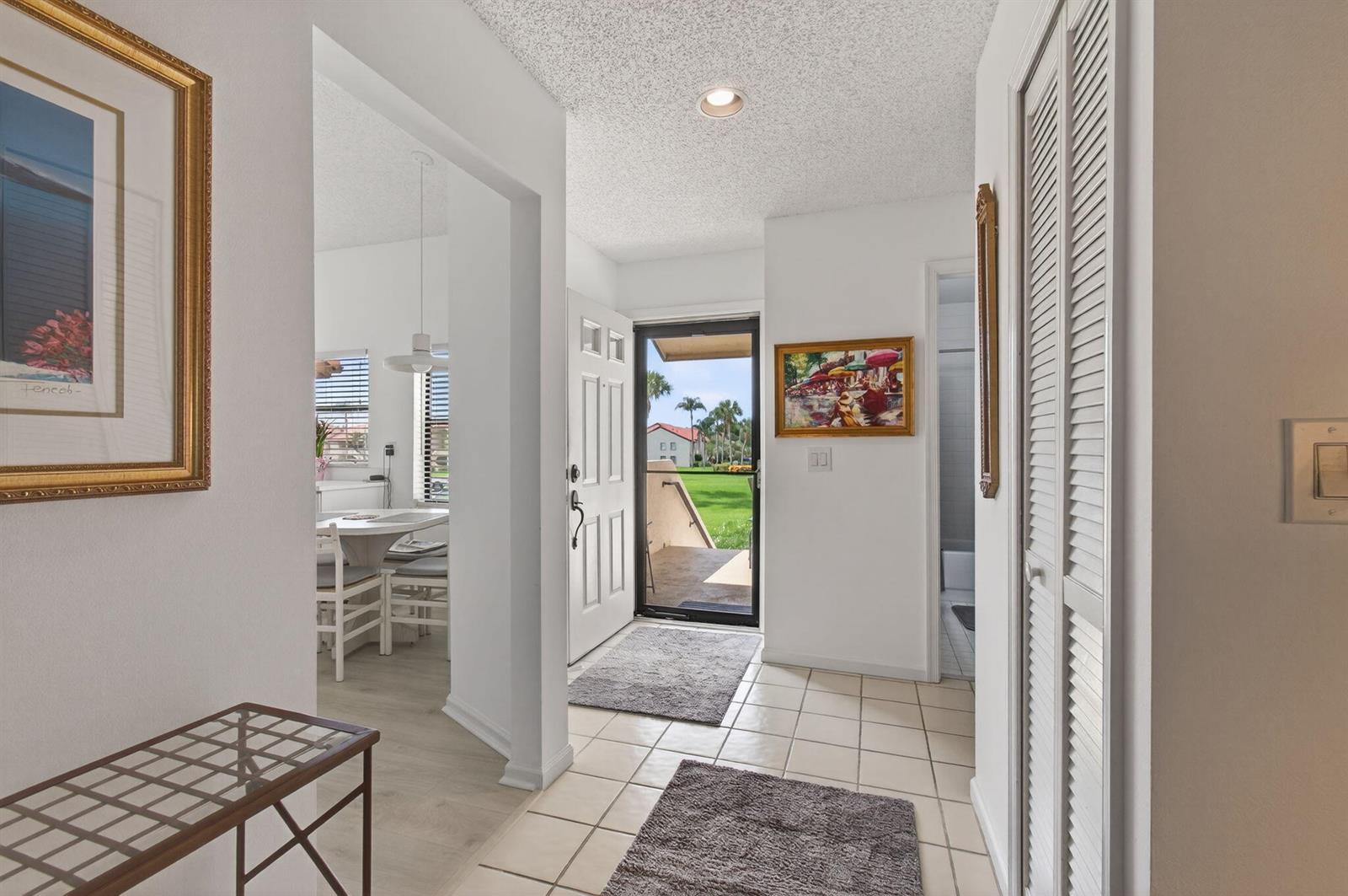 An entryway with tiled floors, a white door, and a view of a grassy exterior — 5947 Parkwalk Drive, Boynton Beach FL 33472, BOYNTON BEACH, FL