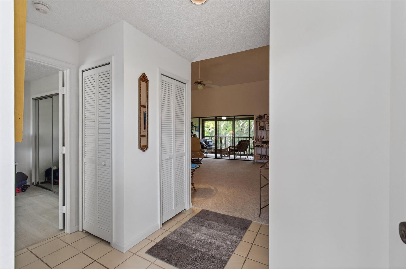 A tiled entryway leads to a carpeted living area with a sliding glass door balcony view — 5947 Parkwalk Drive, Boynton Beach FL 33472, BOYNTON BEACH, FL