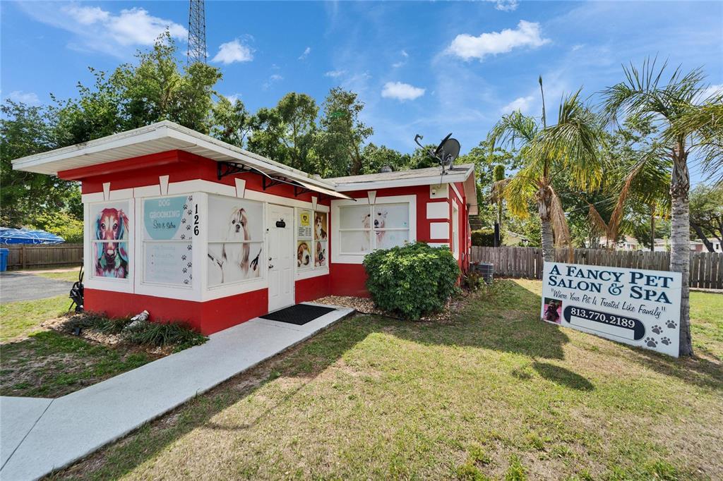 A small, red-painted commercial building with a pet grooming sign stands on a grassy lot — 126 RIDGEWOOD AVENUE, BRANDON, FL