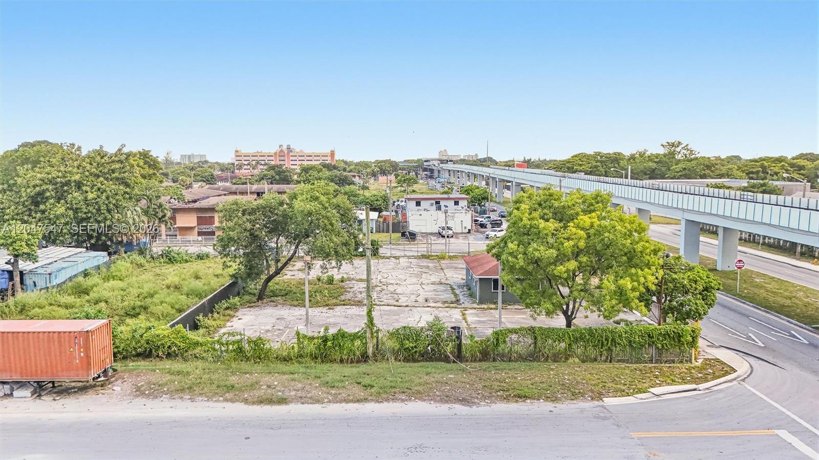 An elevated view shows a vacant concrete lot with a small building and surrounding trees — 6801 NW 27th Ave, Miami FL 33147, MIAMI, FL