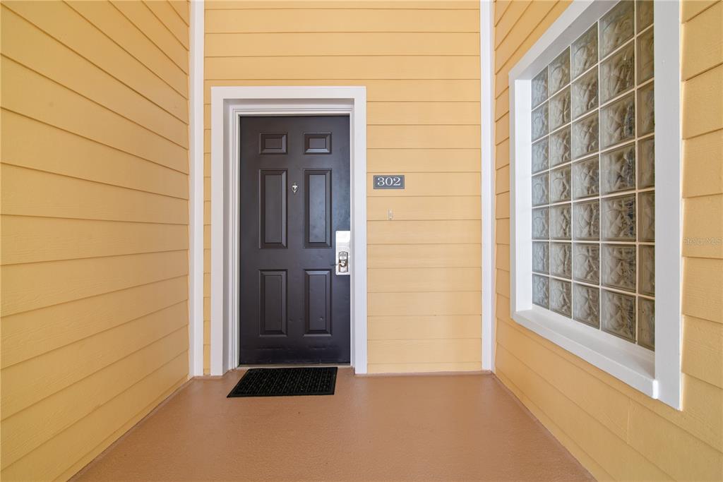 A dark front door with a number 302 sign sits on a yellow-sided porch — 3060 PIRATES RETREAT COURT UNIT 302, KISSIMMEE, FL