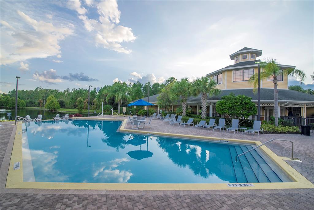 A swimming pool with a surrounding patio and a clubhouse building under a cloudy sky — 3060 PIRATES RETREAT COURT UNIT 302, KISSIMMEE, FL