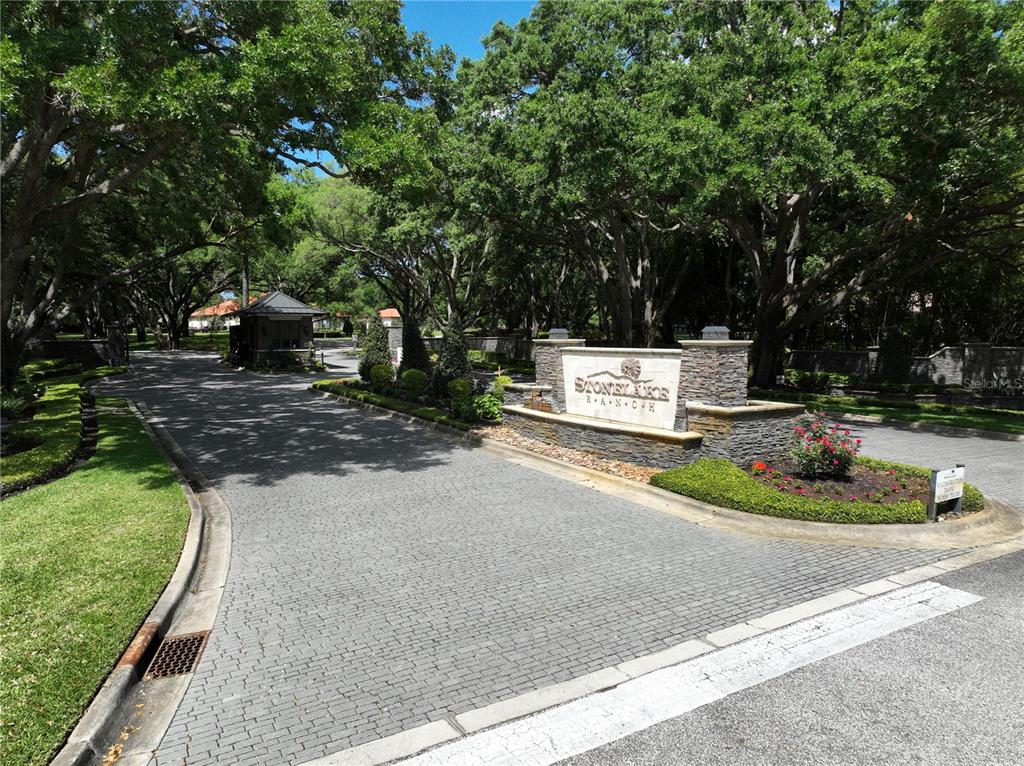 The entrance to Stonelake Ranch features a stone monument sign, paved driveway, and mature trees — 12322 STONELAKE RANCH BOULEVARD, THONOTOSASSA, FL