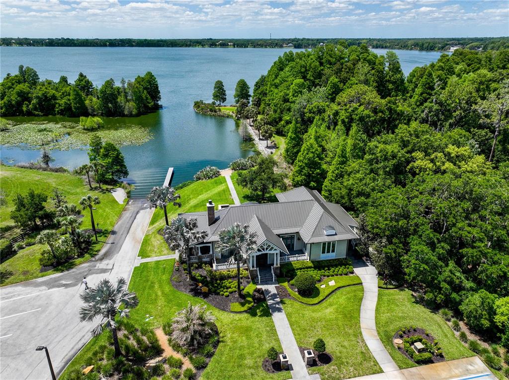 An aerial view shows a house with a metal roof situated near a lake — 12322 STONELAKE RANCH BOULEVARD, THONOTOSASSA, FL