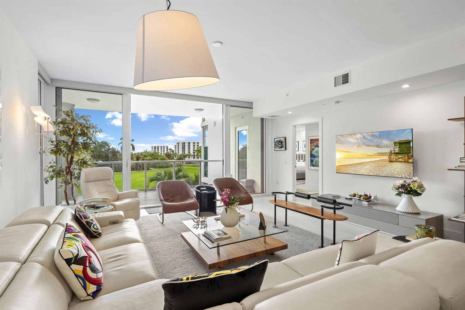 A modern living room features a large sectional sofa, glass coffee table, and balcony view — 20155 Boca West Drive # C201, Boca Raton FL 33434, BOCA RATON, FL