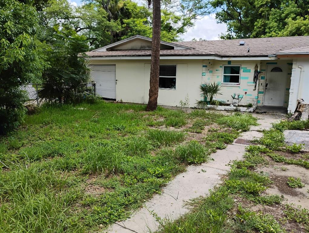 A single-story house with a white exterior, a garage, and an overgrown front yard — 2157 RAILROAD AVENUE, SAFETY HARBOR, FL