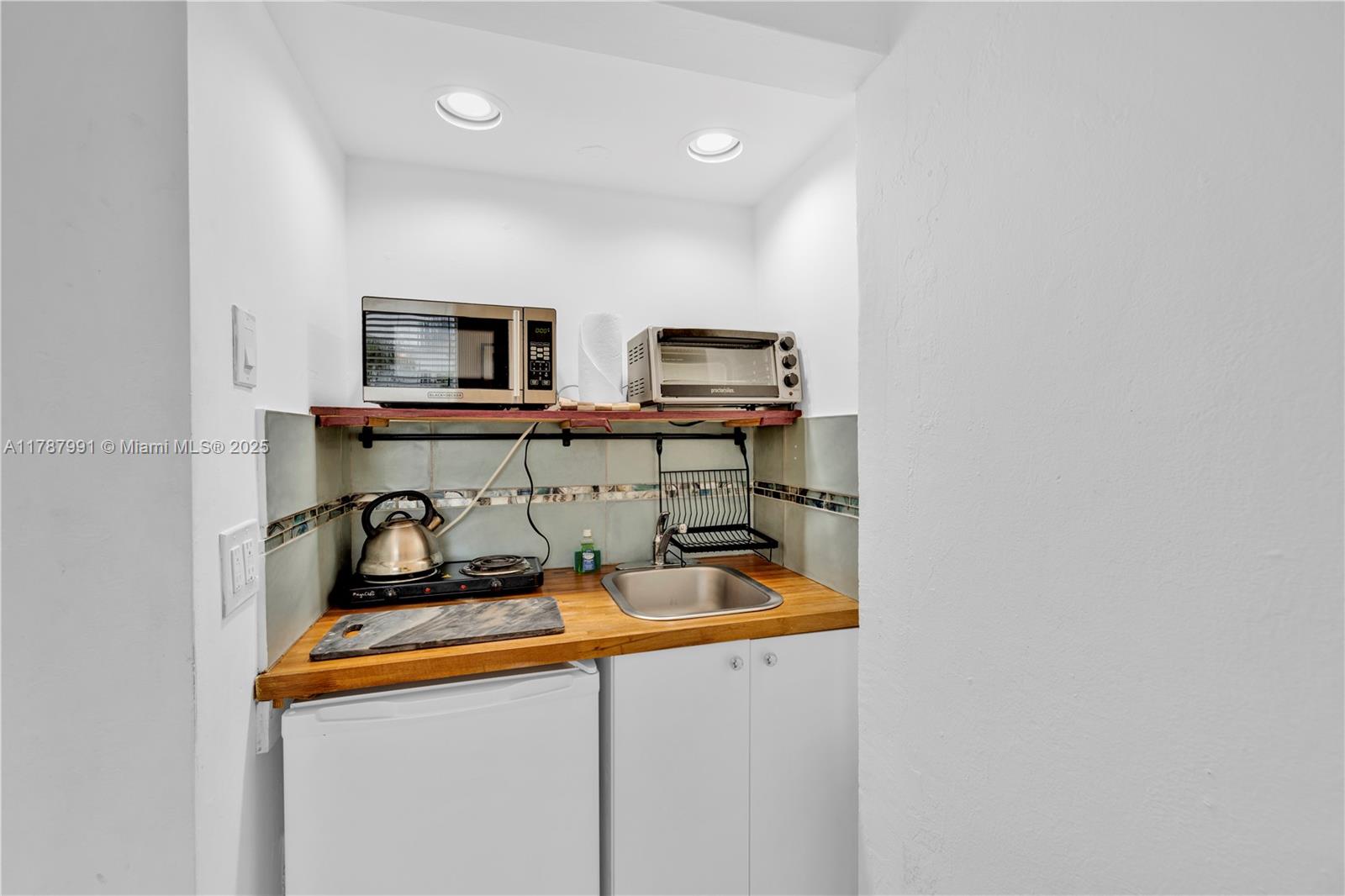 A small kitchenette features a wooden countertop, sink, hot plate, microwave, and toaster oven — 255 W 24th St # 136, Miami Beach FL 33140, MIAMI BEACH, FL