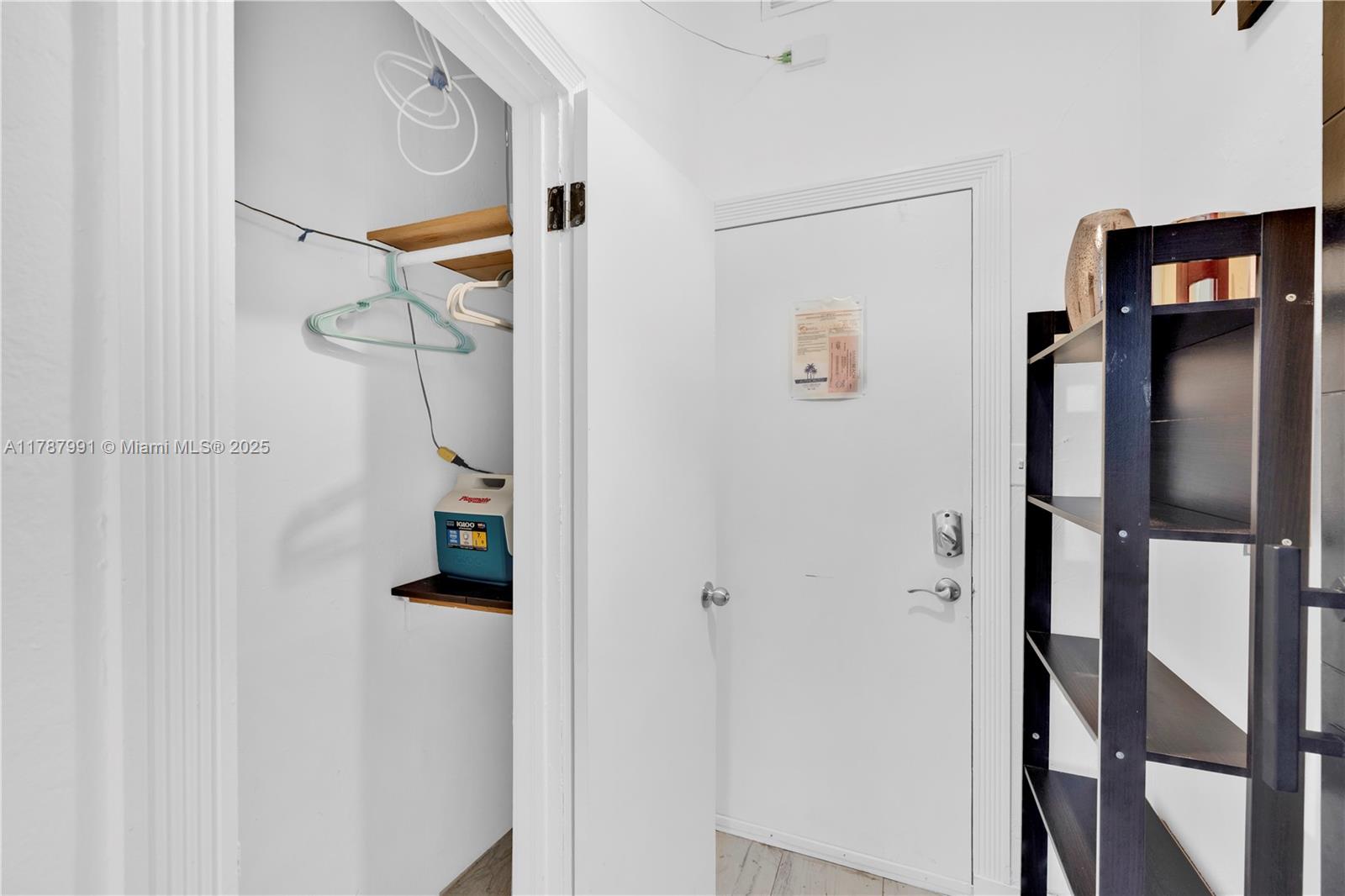 A small closet with a shelf and a cooler sits beside a white door — 255 W 24th St # 136, Miami Beach FL 33140, MIAMI BEACH, FL