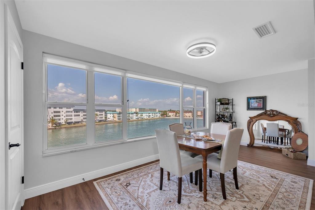 A dining room with a large window overlooking a waterway, wood floors, and area rug — 6025 SHORE BOULEVARD S UNIT 405, GULFPORT, FL