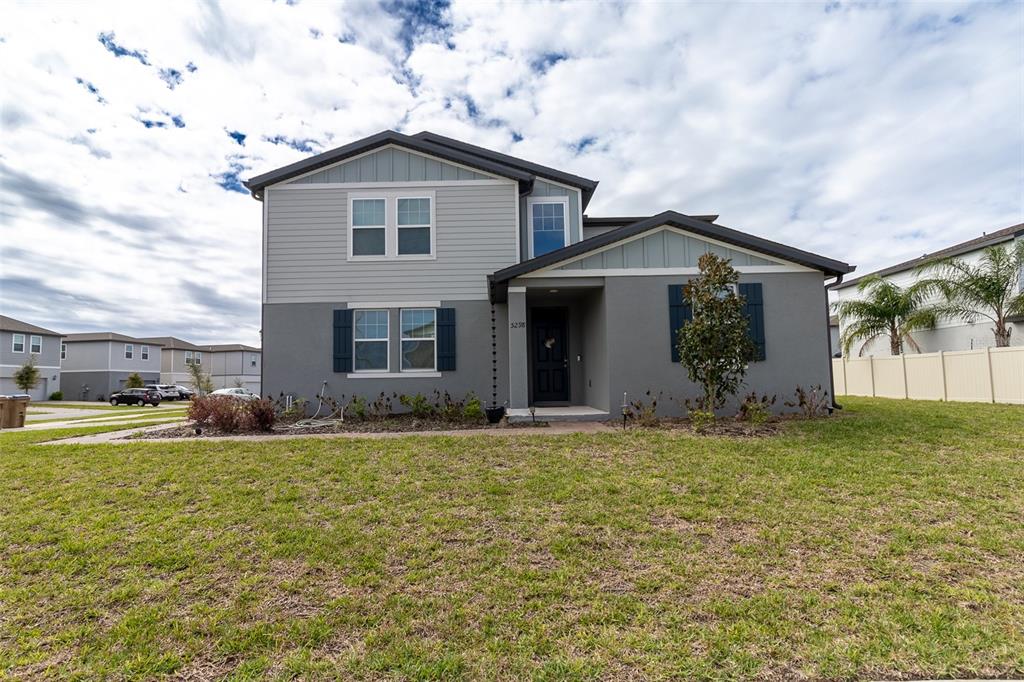 A two-story house with gray stucco and siding features a front porch and lawn — 5298 MEREDREW LANE, ST CLOUD, FL