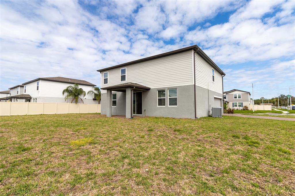 The rear exterior of a two-story house features a covered patio and a grassy yard — 5298 MEREDREW LANE, ST CLOUD, FL