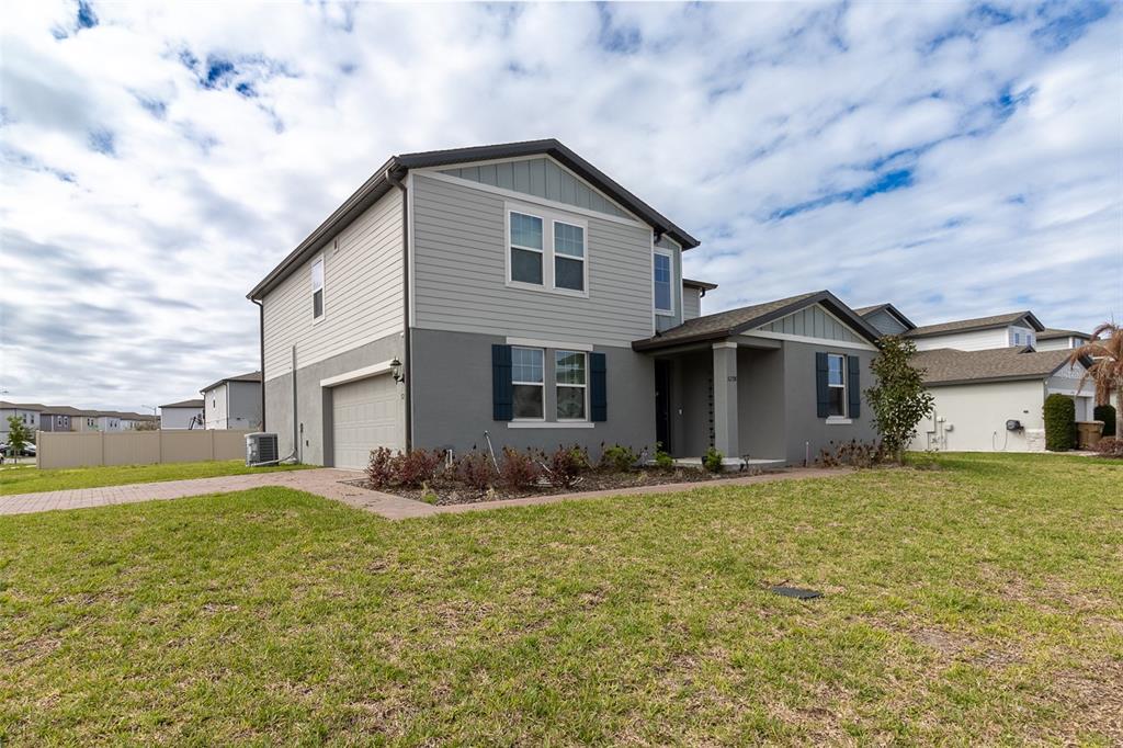 A two-story house with gray stucco and siding, a garage, and a paved walkway — 5298 MEREDREW LANE, ST CLOUD, FL