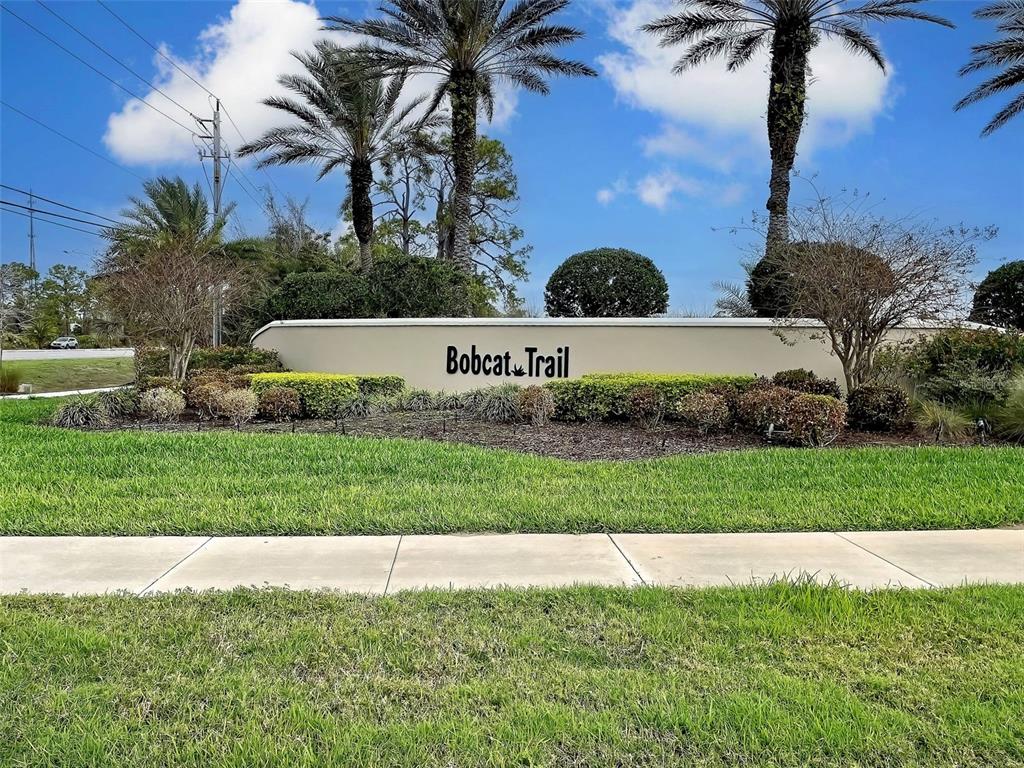 A beige community entrance wall with the text Bobcat Trail sits behind a grassy lawn — 1645 PALMETTO PALM WAY, NORTH PORT, FL
