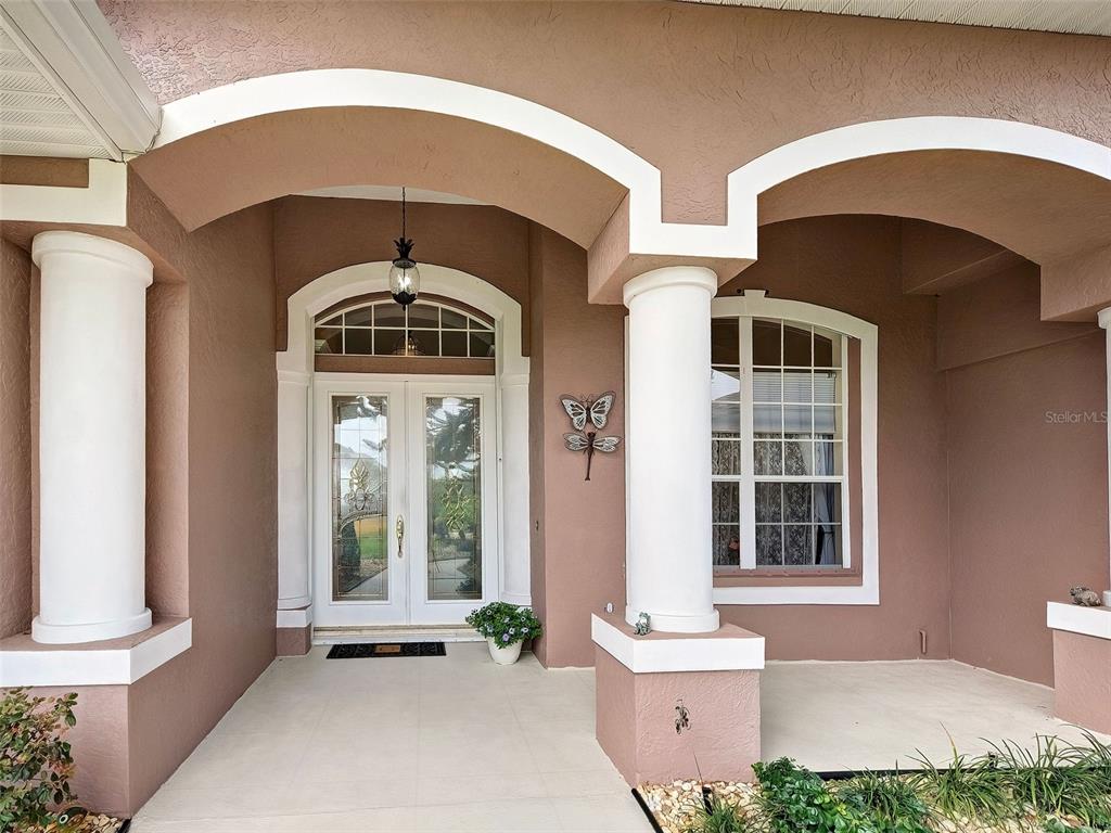A covered front porch features white columns, arched entryways, and double glass front doors — 1645 PALMETTO PALM WAY, NORTH PORT, FL