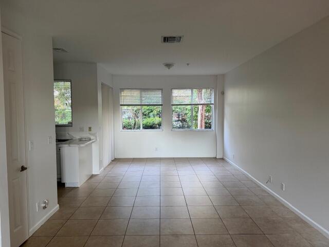 An empty living room features light-colored tile flooring, white walls, and two large windows — 4459 Cotswold Hills Drive, FL 33461, FL