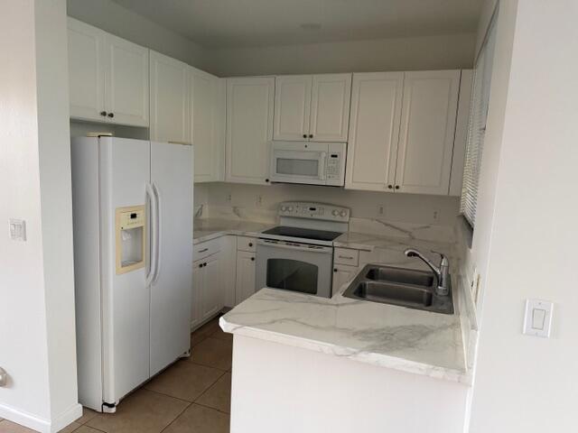 A kitchen features white cabinets, stainless steel appliances, and white marble-patterned countertops — 4459 Cotswold Hills Drive, FL 33461, FL