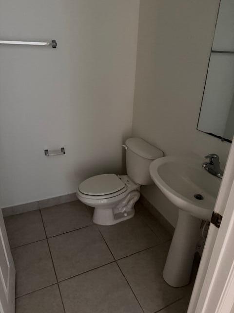 A small bathroom features a white toilet, a pedestal sink, and light-colored floor tiles — 4459 Cotswold Hills Drive, FL 33461, FL