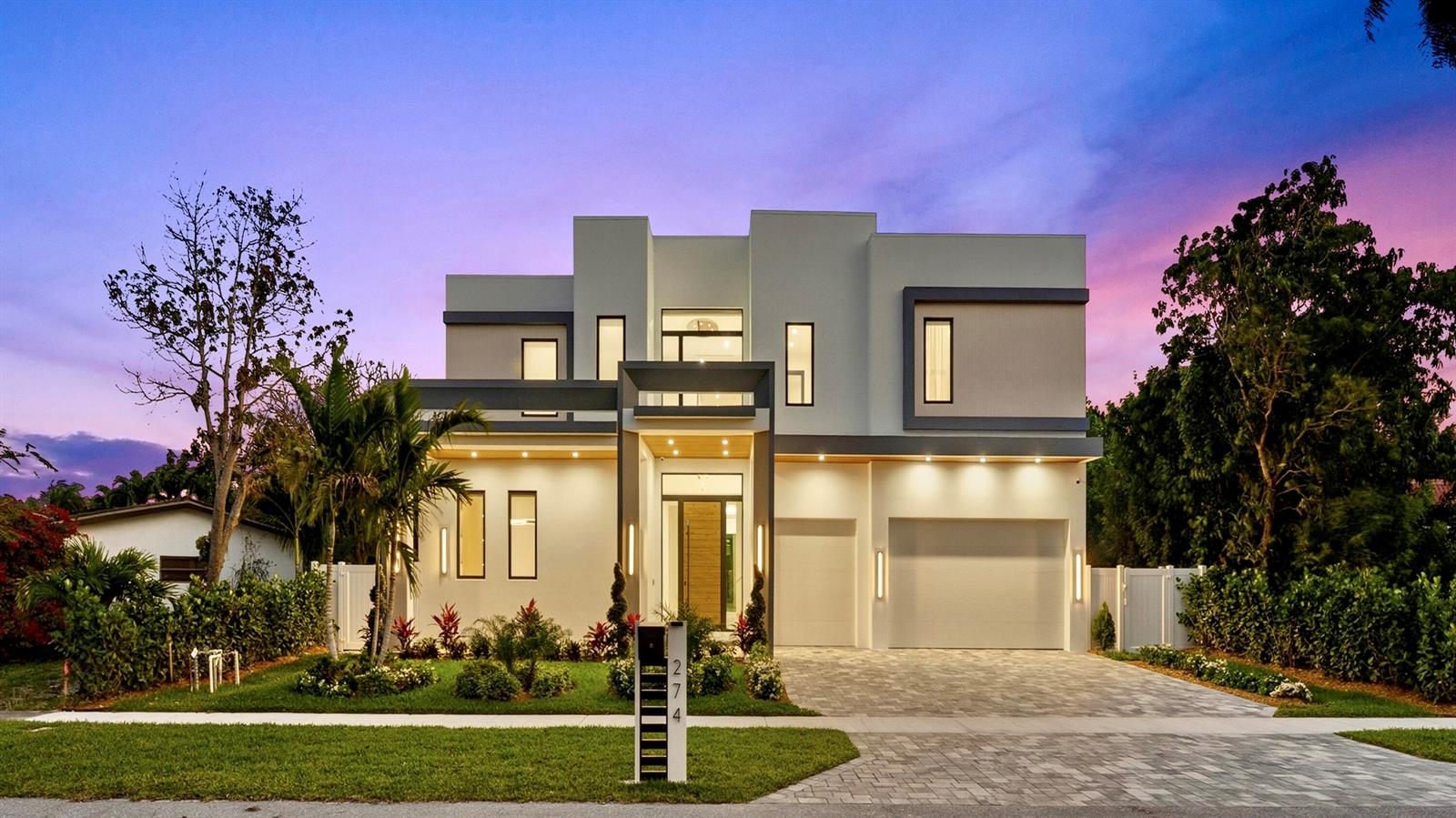 A modern two-story house with a paved driveway, garage, and landscaped front yard at dusk — 274 NE 3rd Court, Boca Raton FL 33432, BOCA RATON, FL