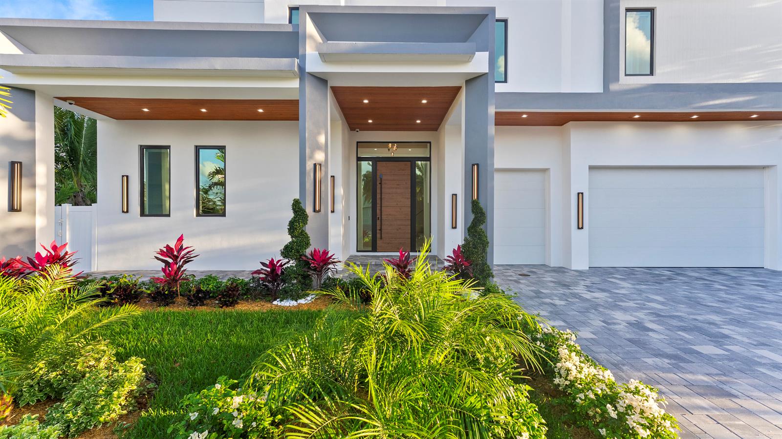 A modern white house exterior features a wood-paneled entryway, gray accents, and landscaped front yard — 274 NE 3rd Court, Boca Raton FL 33432, BOCA RATON, FL