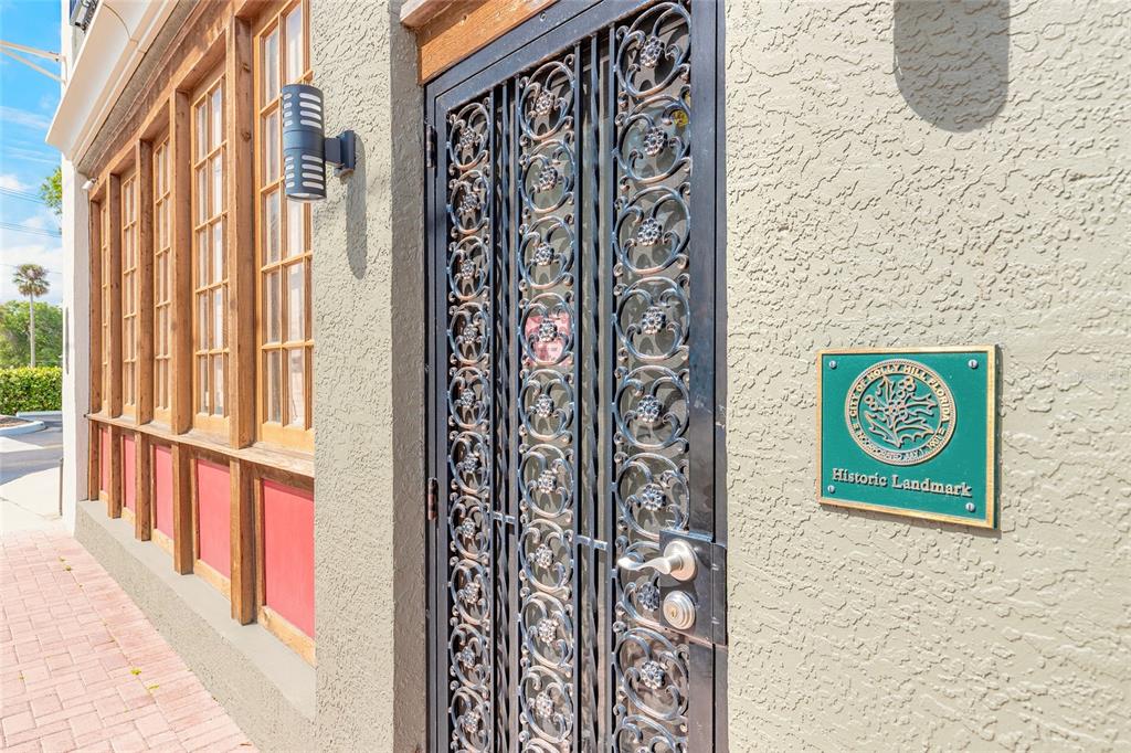 An exterior view of a building with a decorative iron door and a historic landmark plaque — 1112 RIVERSIDE DRIVE, DAYTONA BEACH, FL