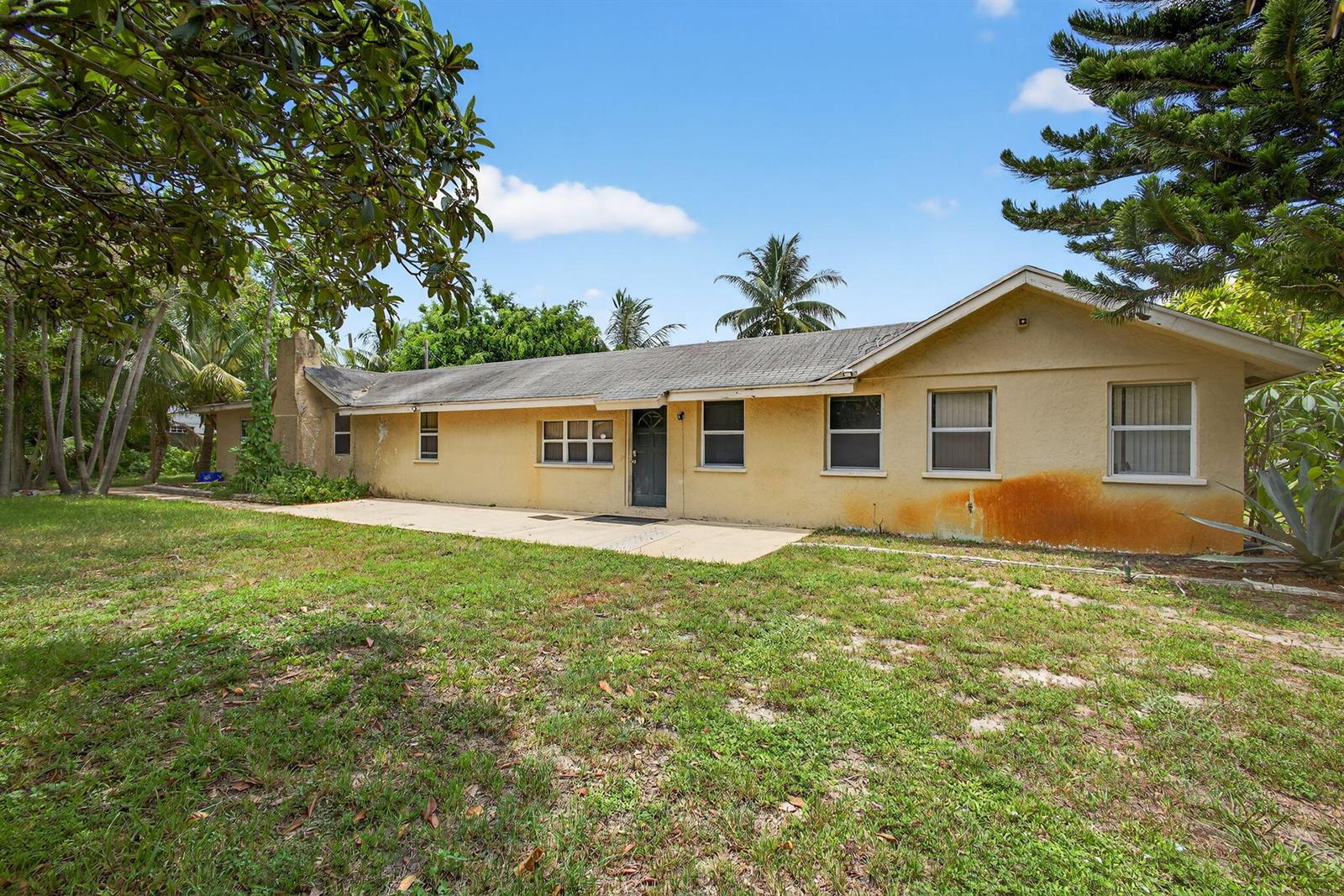 A single-story yellow stucco house with a concrete patio and a grassy yard — 129 Fleming Avenue, FL 33463, FL
