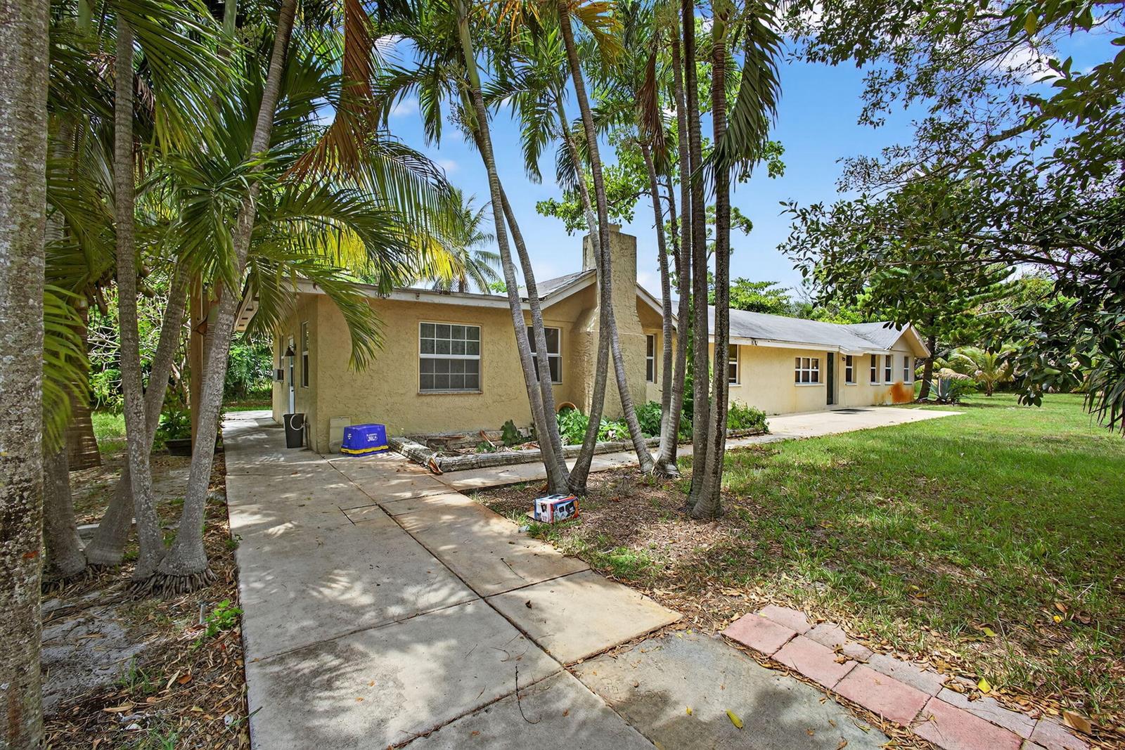 A single-story yellow house with a concrete walkway and palm trees in the yard — 129 Fleming Avenue, FL 33463, FL