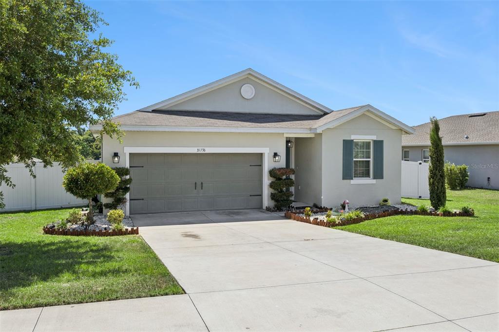 A single-story house features a gray garage, a front entrance, and a landscaped front yard — 31736 BROADWATER AVENUE, LEESBURG, FL