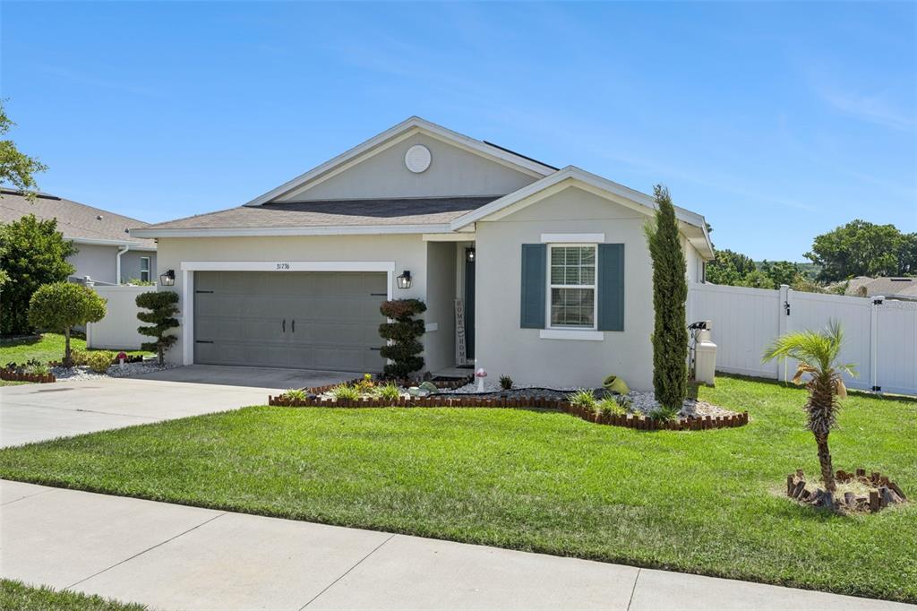 A single-story house with a two-car garage, light-colored stucco exterior, and a manicured lawn — 31736 BROADWATER AVENUE, LEESBURG, FL