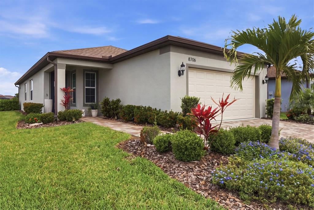 A single-story house with a beige stucco exterior, a two-car garage, and landscaped front yard — 8706 OCEAN TIDES COVE, PARRISH, FL