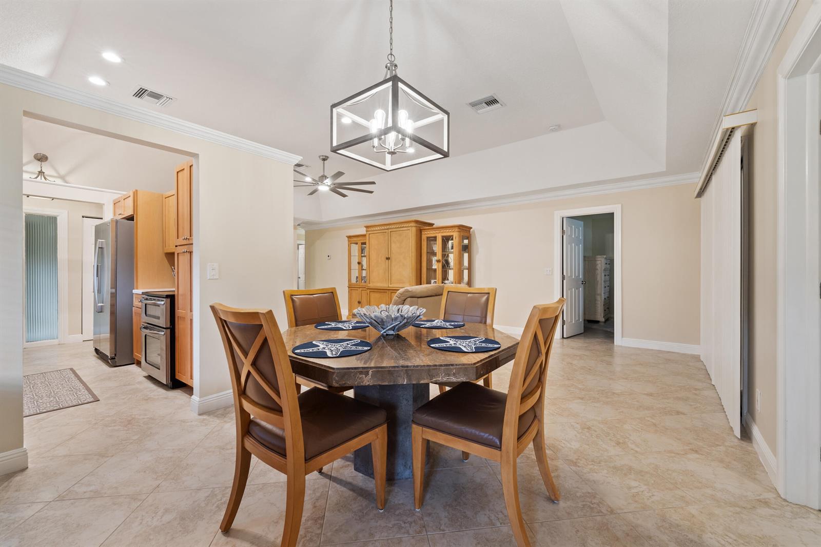 A dining area features a stone-topped table, four wooden chairs, and a modern pendant light — 109 Half Moon Circle # C, Jupiter FL 33458, JUPITER, FL