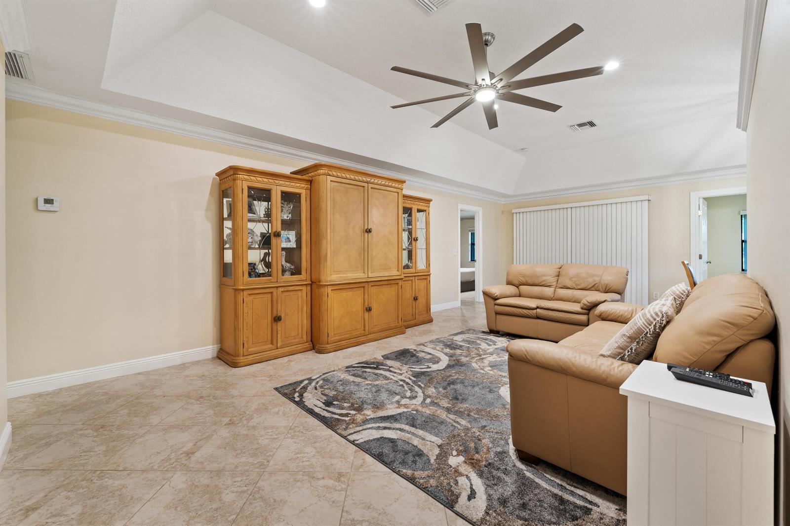 A living room features a large wooden entertainment center, tan leather sofas, and tile flooring — 109 Half Moon Circle # C, Jupiter FL 33458, JUPITER, FL